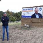 Andrzej Bachan przy swoim słomianym billboardzie w Rychnowach. Fot. Wojciech Piepiorka